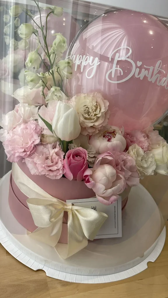 קופסת פרחים אישית מעוצבת עם בלון Happy Birthday ופרחים בגווני ורוד ולבן משלוח מהיר